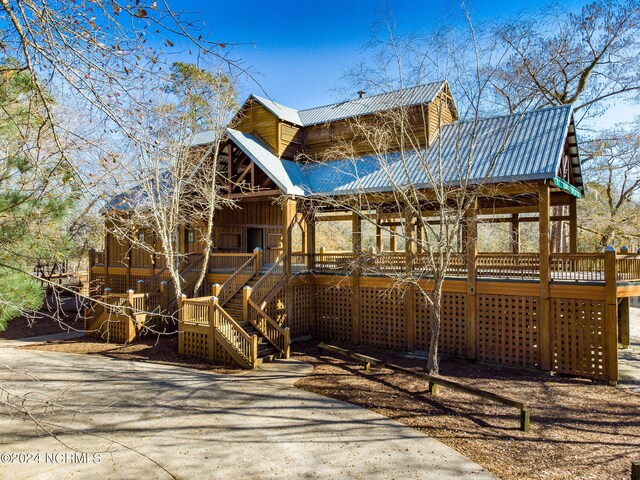 view of front of house featuring a deck, metal roof, and stairway