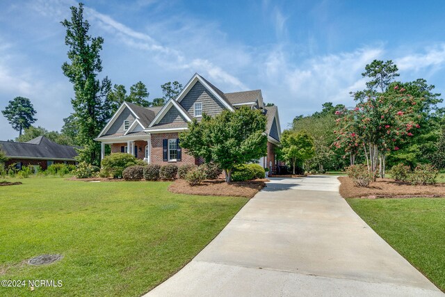 craftsman house with a front yard, brick siding, and driveway