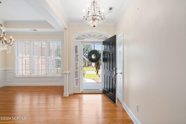 foyer featuring crown molding, a healthy amount of sunlight, light wood-type flooring, and a notable chandelier