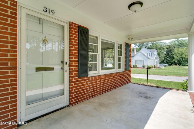 doorway to property with a porch and brick siding