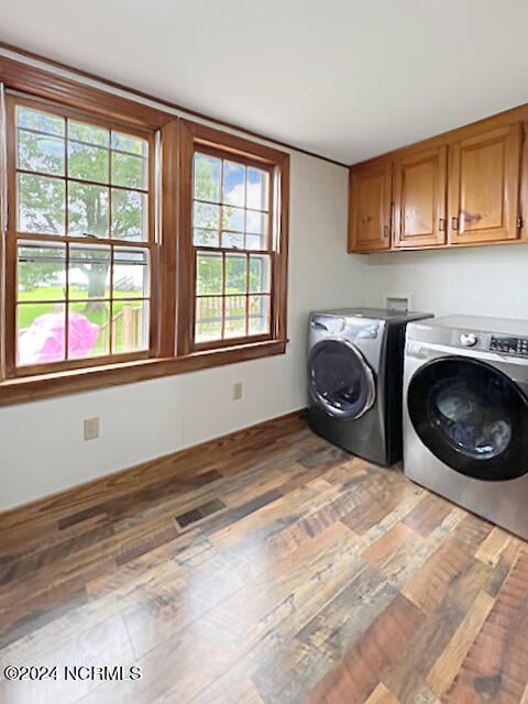 laundry room featuring cabinets, independent washer and dryer, and hardwood / wood-style floors