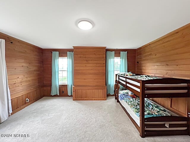 carpeted bedroom featuring wooden walls