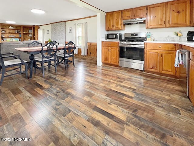 kitchen with dark wood-type flooring, appliances with stainless steel finishes, and crown molding