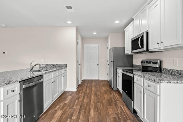 kitchen featuring appliances with stainless steel finishes, sink, light stone counters, white cabinets, and dark wood-type flooring