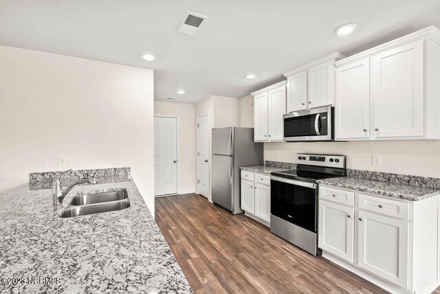 kitchen with stainless steel appliances, white cabinetry, dark hardwood / wood-style floors, sink, and light stone countertops