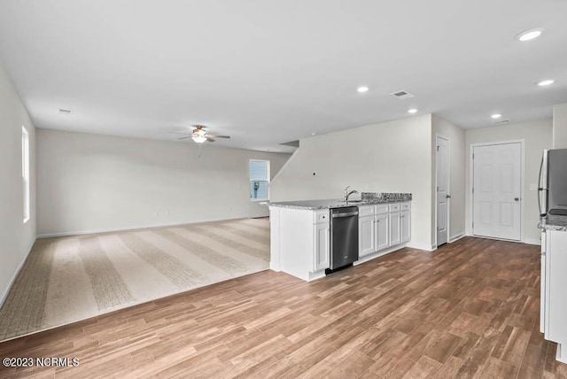 kitchen featuring light stone counters, a sink, white cabinets, open floor plan, and appliances with stainless steel finishes