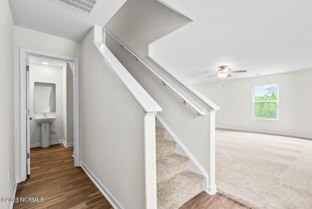 staircase featuring ceiling fan, wood finished floors, visible vents, and baseboards