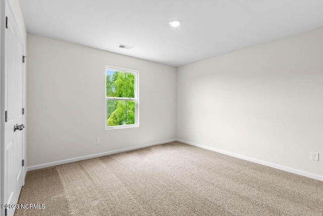 unfurnished room with carpet, visible vents, and baseboards