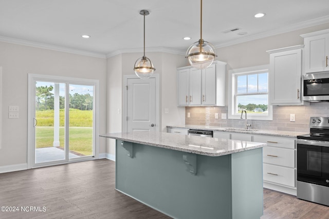 kitchen featuring a kitchen breakfast bar, tasteful backsplash, appliances with stainless steel finishes, hardwood / wood-style flooring, and crown molding