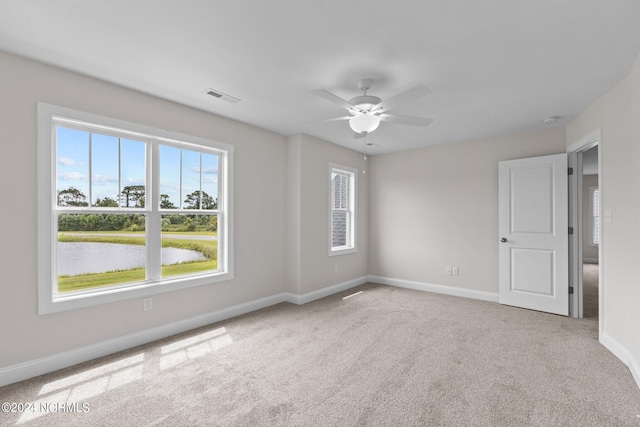 carpeted spare room with ceiling fan and a water view