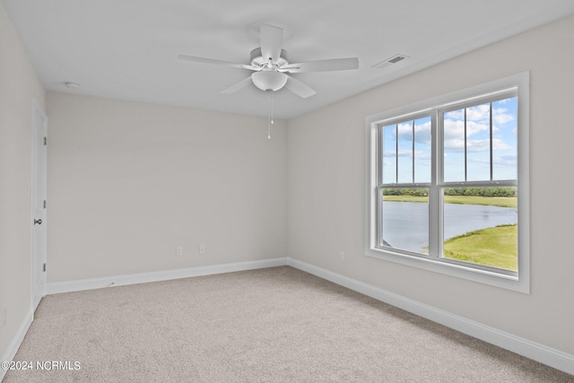 carpeted spare room with ceiling fan and a water view