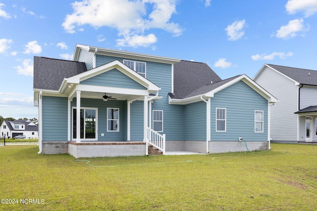 rear view of property featuring ceiling fan and a yard