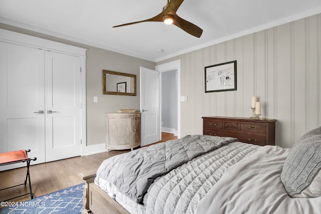 bedroom featuring light wood-style flooring, a ceiling fan, baseboards, a closet, and crown molding