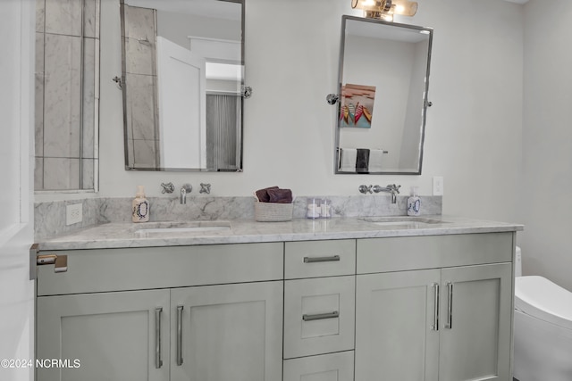 bathroom with a sink, toilet, and double vanity