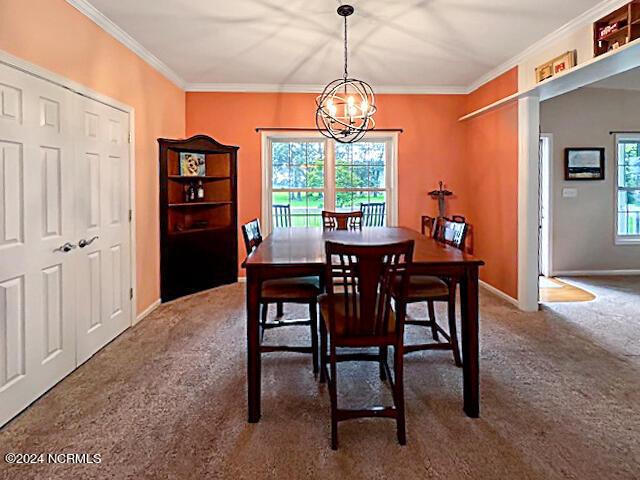 carpeted dining room with a chandelier, a wealth of natural light, crown molding, and baseboards