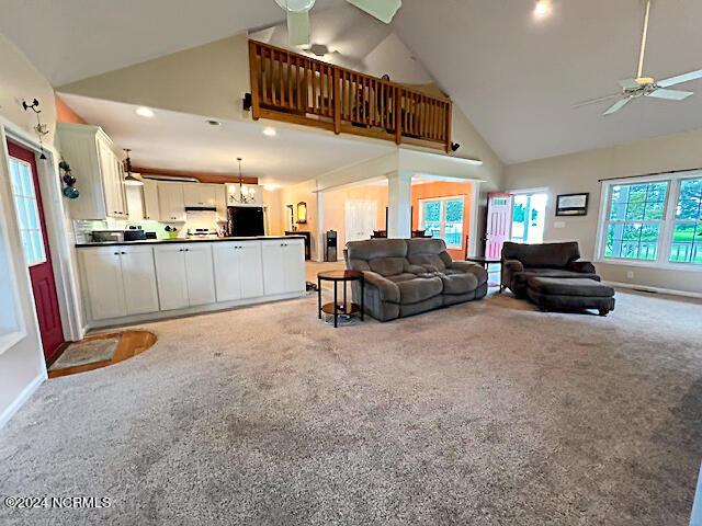 living room featuring light carpet, baseboards, high vaulted ceiling, and a ceiling fan