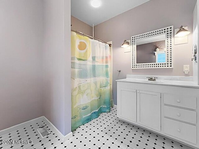 full bath with a shower with curtain, tile patterned floors, baseboards, and vanity