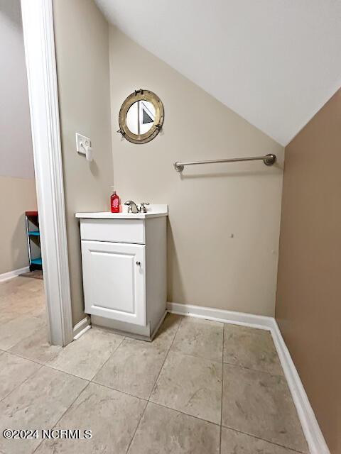 bathroom featuring lofted ceiling, vanity, and baseboards