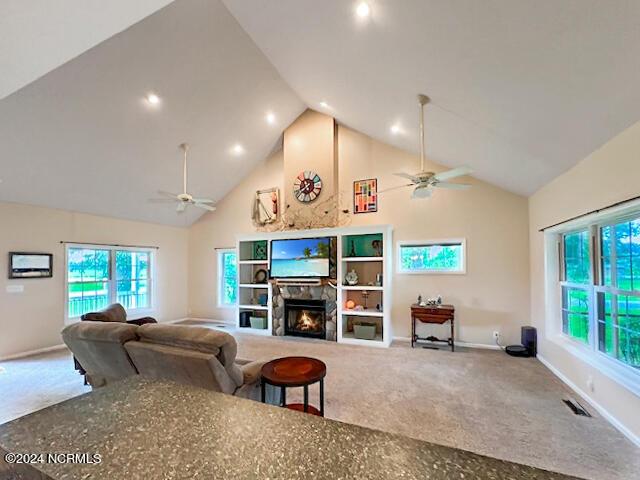 living room featuring carpet floors, high vaulted ceiling, ceiling fan, and a fireplace