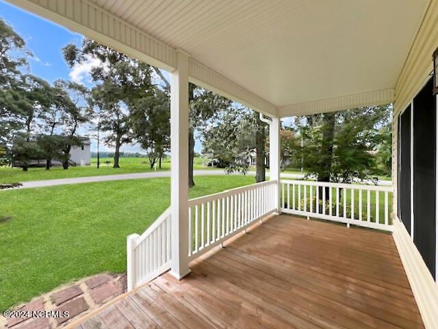 wooden deck featuring a porch and a lawn