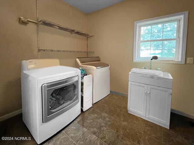 clothes washing area featuring independent washer and dryer, a sink, cabinet space, and baseboards