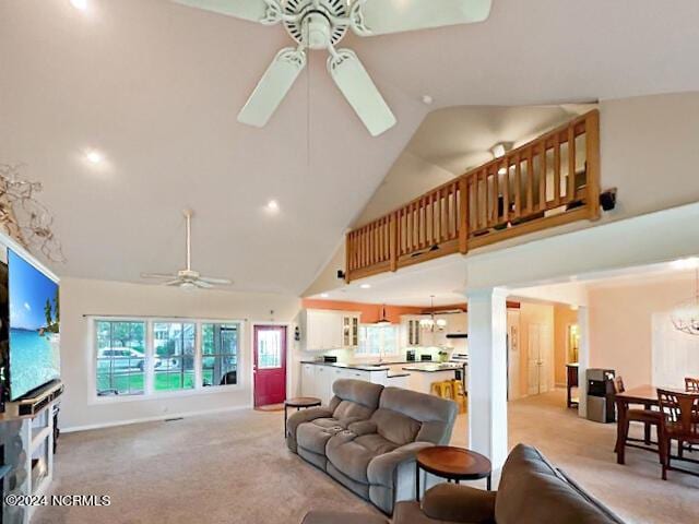 living room featuring ceiling fan with notable chandelier, high vaulted ceiling, and light carpet