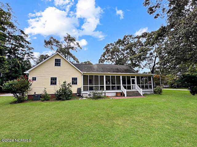 rear view of house featuring a sunroom and a yard