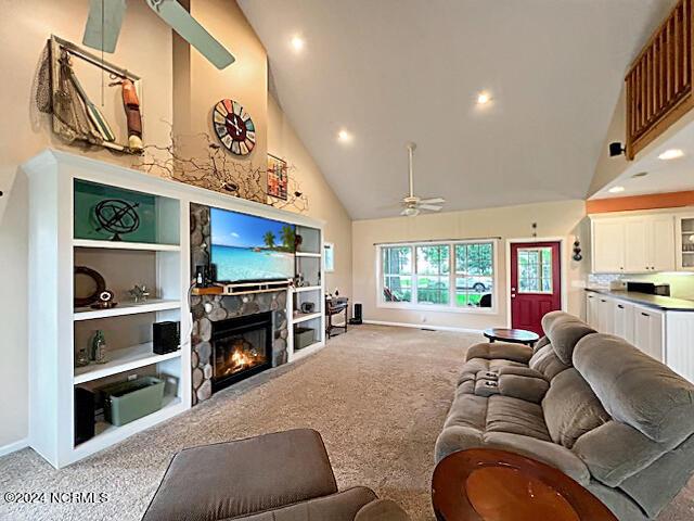 carpeted living room featuring built in features, ceiling fan, a stone fireplace, high vaulted ceiling, and baseboards