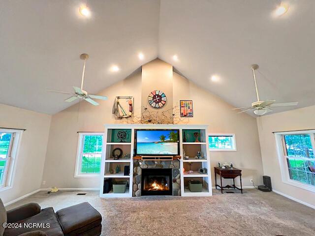 living room with carpet, high vaulted ceiling, a ceiling fan, and a stone fireplace