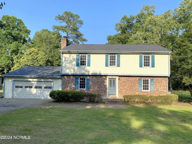 colonial home with an attached garage, brick siding, driveway, a chimney, and a front yard