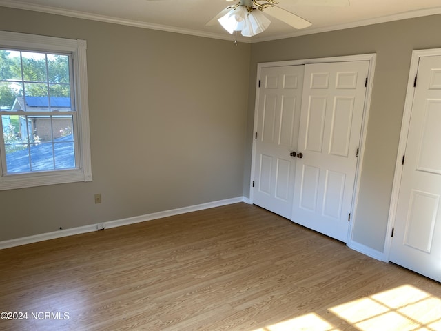 unfurnished bedroom featuring ornamental molding, a closet, baseboards, and light wood finished floors