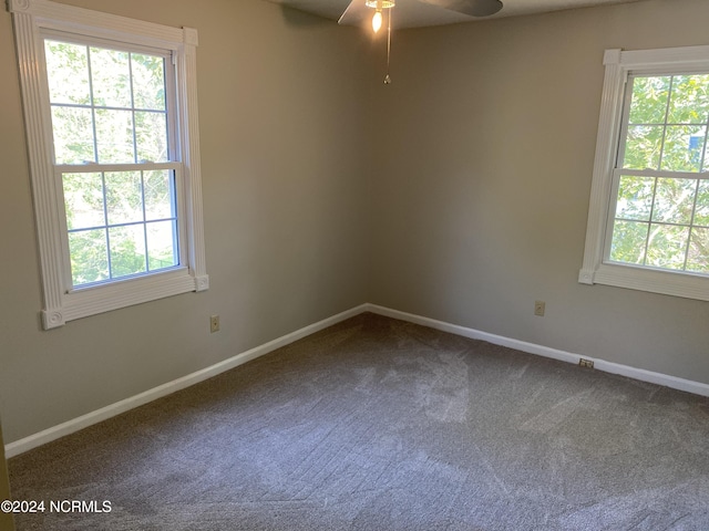 unfurnished room with baseboards, dark colored carpet, and a ceiling fan