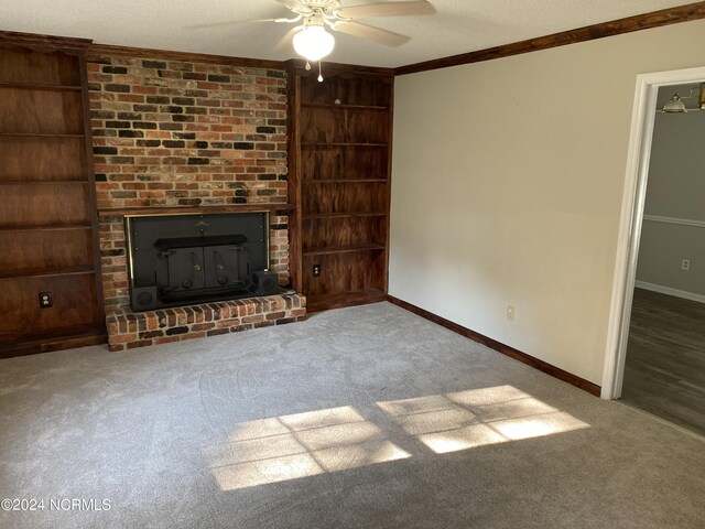 unfurnished living room with ceiling fan, carpet flooring, ornamental molding, a fireplace, and a textured ceiling