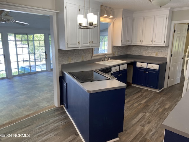 kitchen featuring ornamental molding, stovetop, blue cabinetry, white cabinetry, and a sink