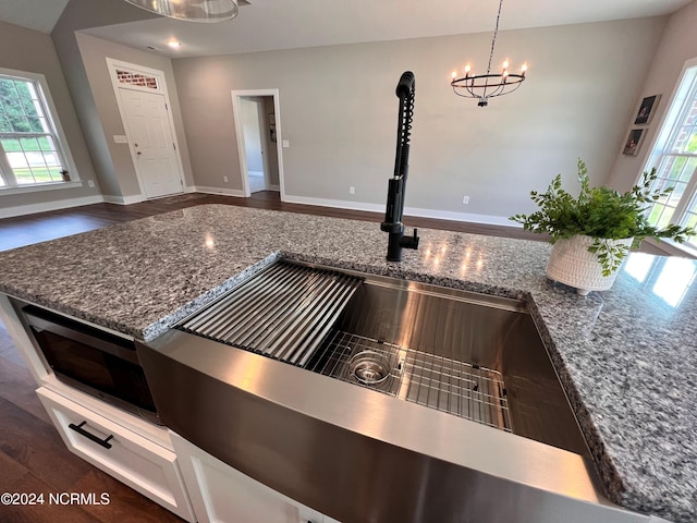 3701 Greystone Dr, Rocky Mount, NC 27804 - details featuring stone counters, a notable chandelier, baseboards, dark wood-style flooring, and a sink