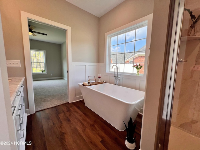 3701 Greystone Dr, Rocky Mount, NC 27804 - bathroom with a freestanding bath, ceiling fan, vanity, wood finished floors, and a wainscoted wall