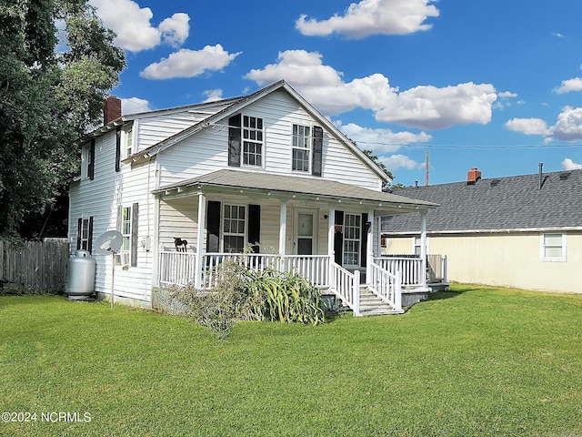 view of front of house featuring covered porch, fence, a chimney, and a front lawn