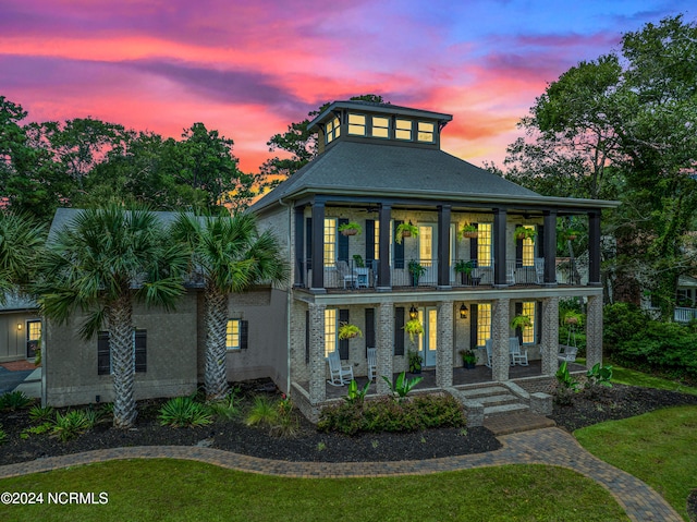 view of front of house featuring a lawn, a balcony, and covered porch