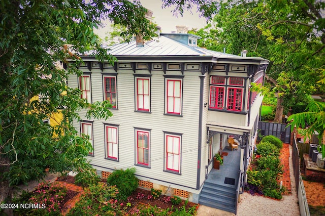 italianate house featuring a standing seam roof, a chimney, and metal roof