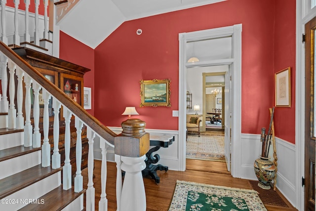 interior space featuring a wainscoted wall, an inviting chandelier, wood finished floors, and lofted ceiling