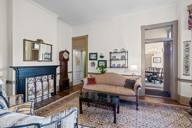 living room with a notable chandelier, a fireplace, ornamental molding, and wood finished floors