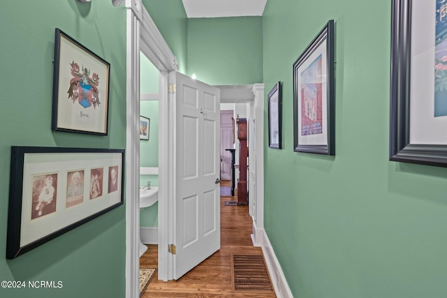 corridor with wood finished floors, visible vents, and baseboards