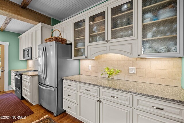 kitchen with white cabinetry, dark hardwood / wood-style flooring, light stone counters, appliances with stainless steel finishes, and beam ceiling