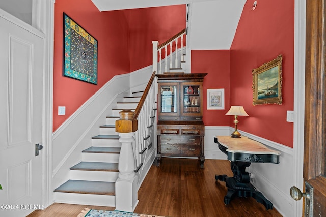 stairway featuring wood finished floors and wainscoting