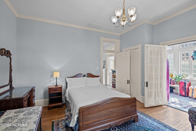 bedroom featuring baseboards, visible vents, wood finished floors, crown molding, and a chandelier