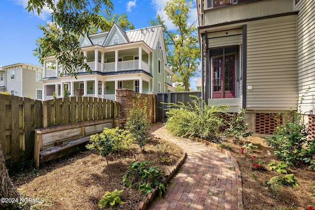 view of front of property with fence private yard, a standing seam roof, metal roof, and a balcony