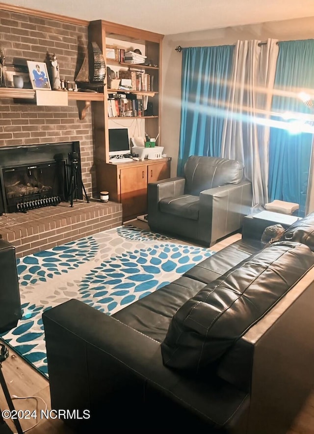 living room featuring brick wall, hardwood / wood-style floors, and a brick fireplace