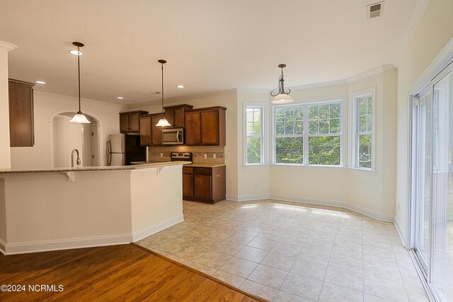 kitchen with light hardwood / wood-style flooring, backsplash, appliances with stainless steel finishes, kitchen peninsula, and crown molding