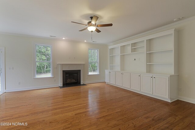 unfurnished living room featuring ceiling fan, crown molding, light hardwood / wood-style floors, and a healthy amount of sunlight