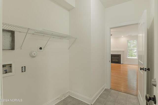 laundry room with hookup for an electric dryer, hookup for a washing machine, a tile fireplace, and wood-type flooring